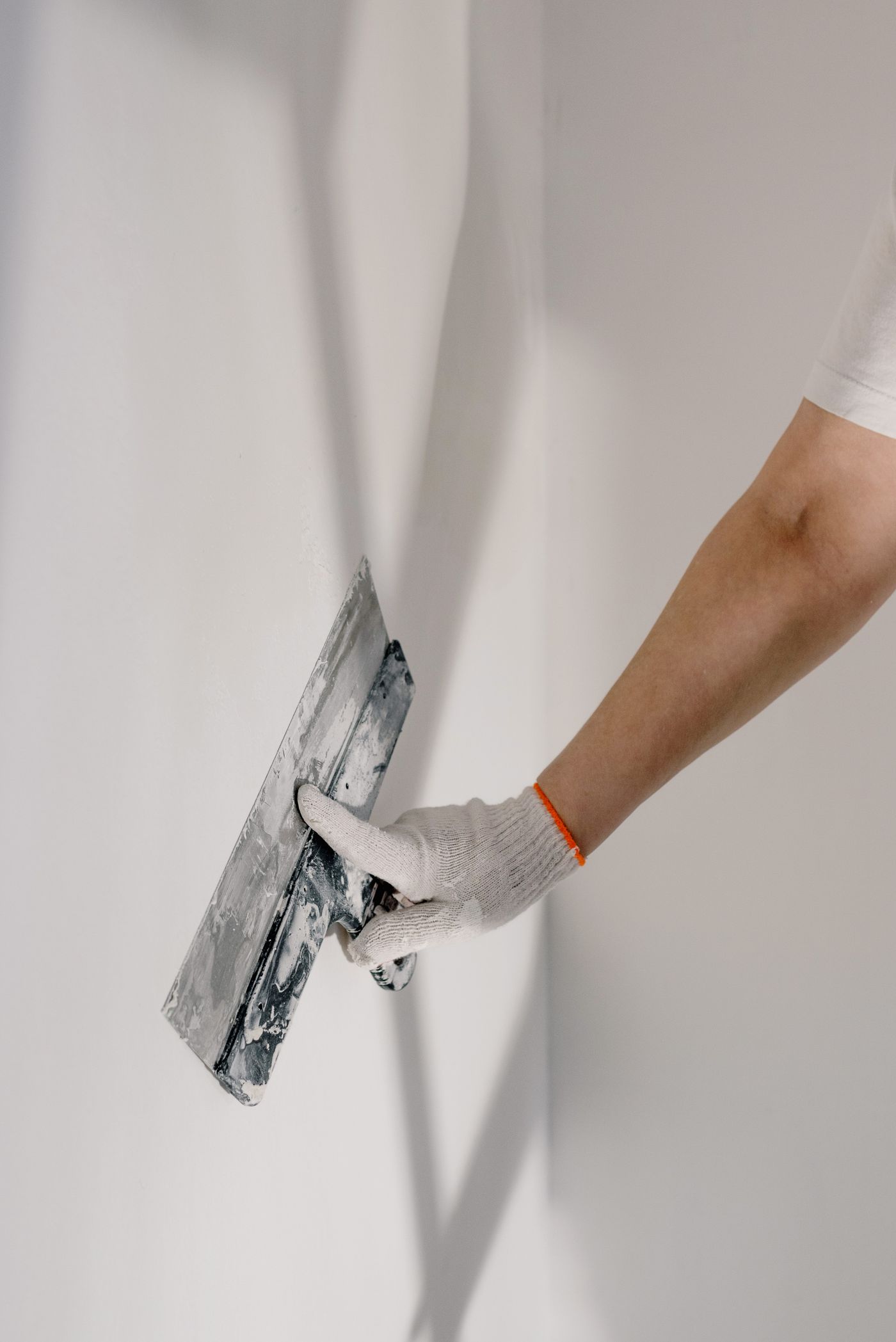 Close-up of a gloved hand smoothing joint compound on a wall