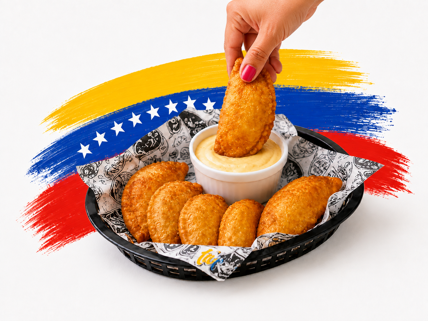 Hand dipping a golden pastelito into sauce with Venezuelan flag accents